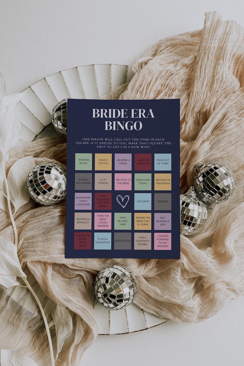 K&ouml;nnte beinhalten: Eine blaue und wei&szlig;e Bingokarte mit dem Titel "Bride Era Bingo". Die Karte hat 25 Felder mit verschiedenen Aufforderungen, die sich auf eine Braut beziehen, wie z. B. "Schwarz tragen", "ein Tattoo haben", "ein Kleid tragen", "&uuml;ber 30 Jahre alt sein" und "aus der Ferne kommen".
