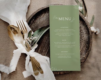 Puede incluir: Una tarjeta de menú verde con la palabra "the MENU" en texto blanco. El menú enumera entrantes, platos principales y postres. La tarjeta está en un plato de madera con una servilleta blanca y cubiertos de oro.