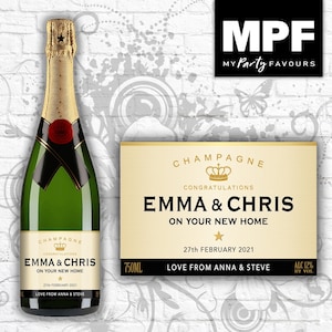May include: A gold and black champagne bottle label with a crown and the text "Champagne Congratulations Emma & Chris On Your New Home 27th February 2021 Love From Anna & Steve".