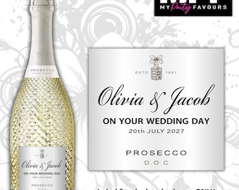 May include: A bottle of Prosecco with a textured glass surface and a custom silver label featuring the text Olivia & Jacob, ON YOUR WEDDING DAY, 20th JULY 2027, PROSECCO D.O.C, and ESTD 1861. The label is also shown separately in a larger view.