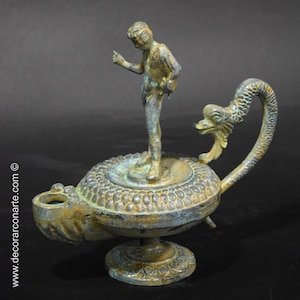 May include: A bronze oil lamp with a dragon-shaped handle and a small bronze figure standing on top. The lamp has a green patina and intricate details.