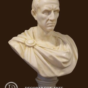 May include: A cream-coloured bust of a man with short hair and a stern expression. The sculpture features a draped garment fastened with a circular clasp. The bust is mounted on a pedestal. The text "-DECORAR.CON.ARTE-" is visible.