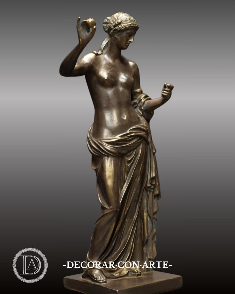 May include: Bronze sculpture of a woman in a flowing robe, holding a fruit in one hand and a cup in the other. The sculpture is on a square base.