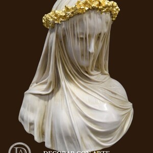 May include: A white marble bust of a woman wearing a veil and a gold leaf crown. The bust is on a gold base.
