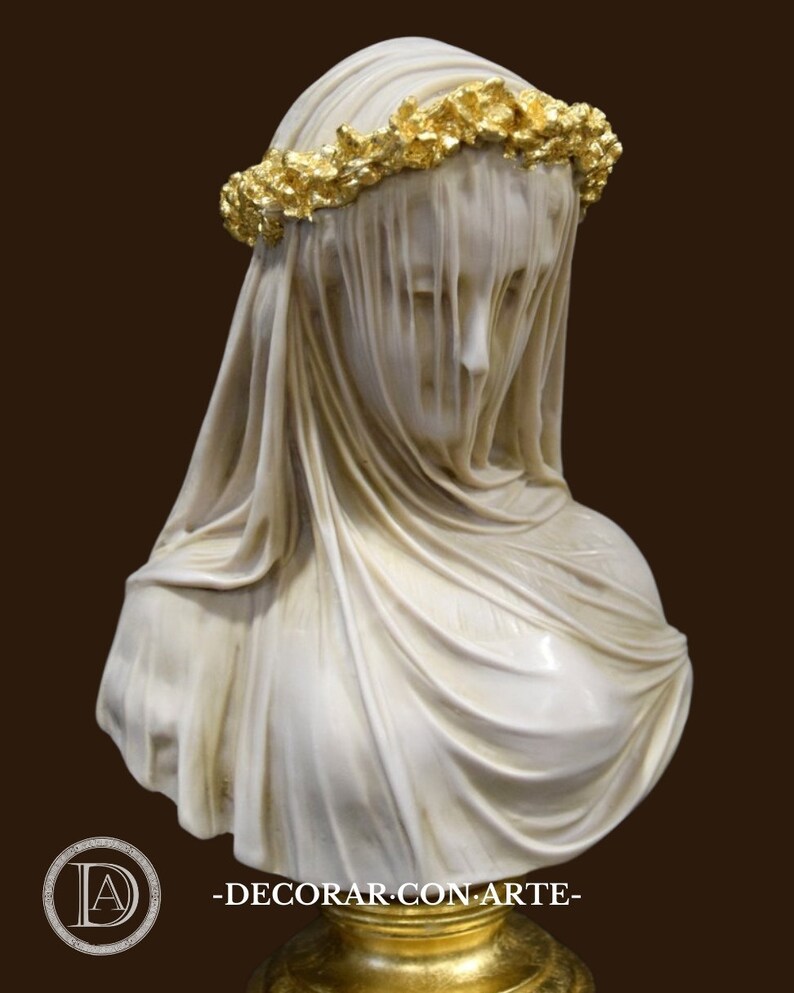 May include: A white marble bust of a woman wearing a veil and a gold leaf crown. The bust is on a gold base.