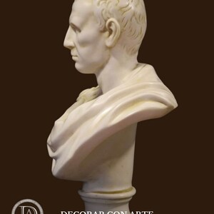 May include: A white marble bust of a man in profile, with detailed facial features and a draped garment. The sculpture is mounted on a pedestal. The bust is a classical art piece, with the text "-DECORAR.CON.ARTE-" in the lower left.