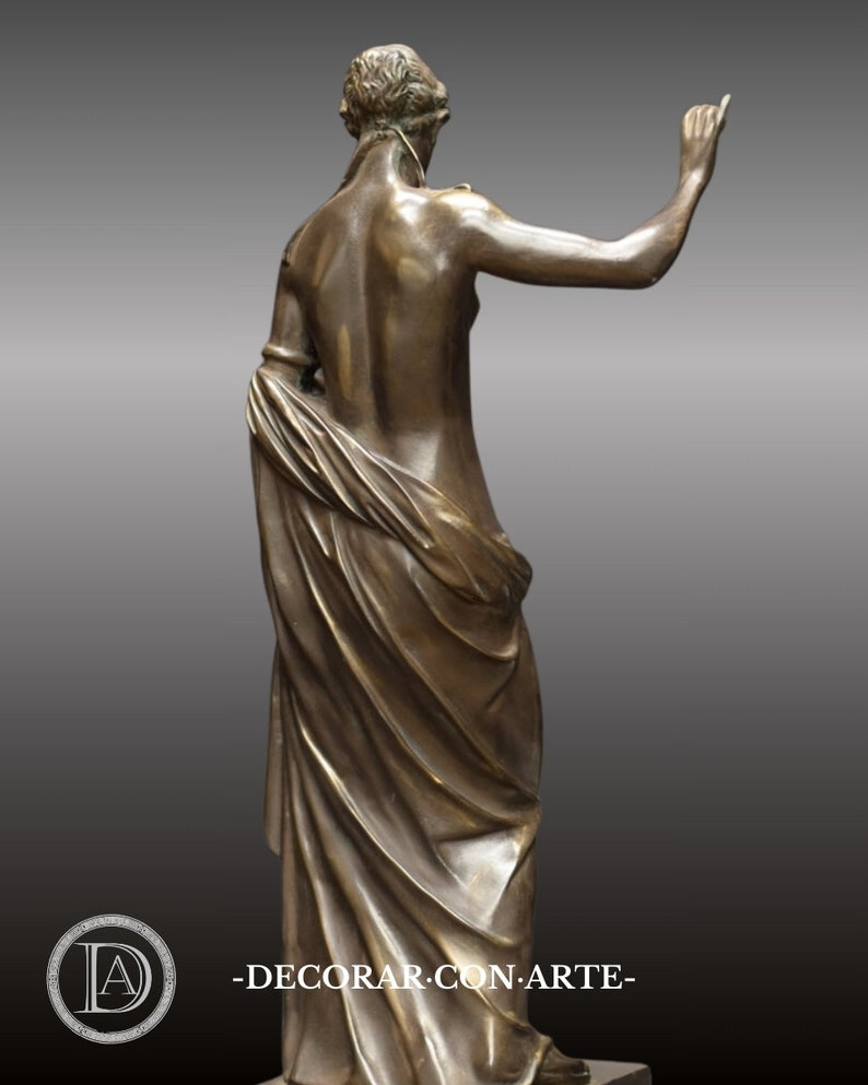 May include: Bronze sculpture of a woman standing with a flowing drapery. The sculpture is in a classical style and depicts a woman with her arm raised.
