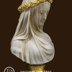 May include: White marble bust of a woman wearing a veil with a gold leaf crown. The bust is on a gold pedestal.