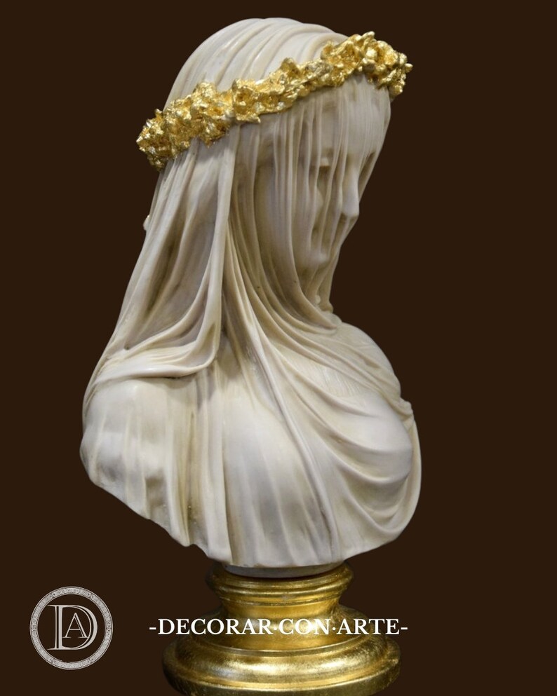 May include: White marble bust of a woman wearing a veil with a gold leaf crown. The bust is on a gold pedestal.
