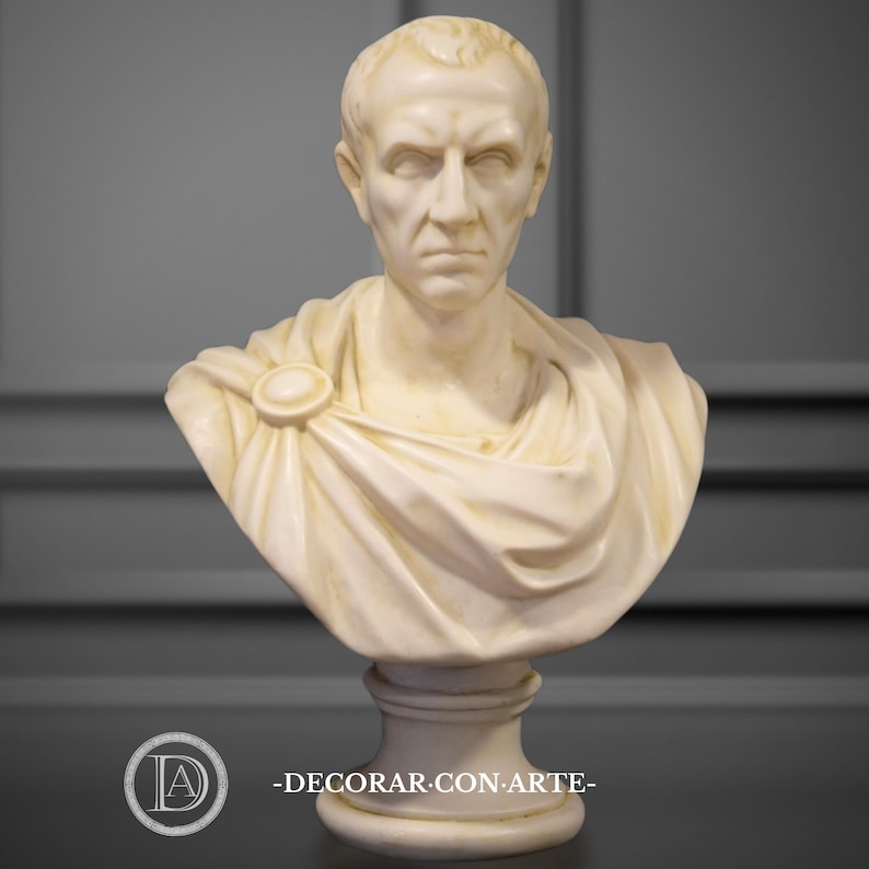 May include: A cream-coloured bust of a man with short hair and a stern expression. The sculpture features a draped garment secured with a circular clasp. The bust is mounted on a pedestal base. The text "-DECORAR.CON.ARTE-" is at the bottom.