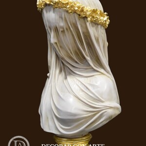 May include: A white marble bust of a woman wearing a veil and a gold leaf crown of flowers. The bust is on a gold-leafed wooden base.