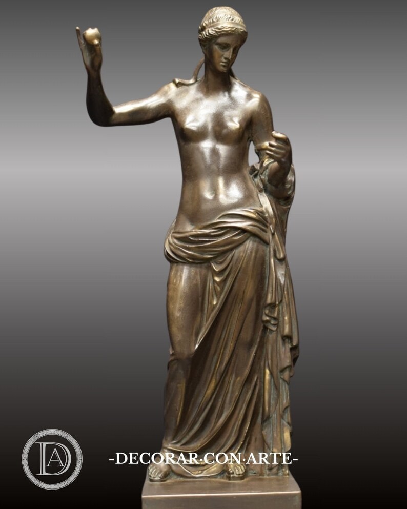 May include: Bronze sculpture of a woman standing with a draped garment and holding an apple in her right hand.