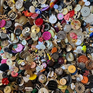 Könnte beinhalten: Eine Sammlung verschiedener Knöpfe in unterschiedlichen Größen, Formen und Farben. Die Knöpfe bestehen aus verschiedenen Materialien wie Kunststoff, Metall und Stoff. Einige Knöpfe haben dekorative Elemente wie Blumenmuster, andere sind schlicht.