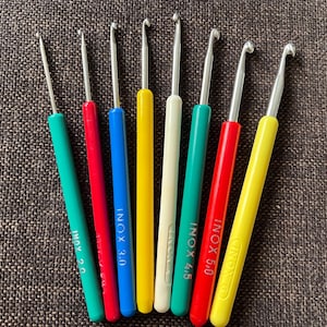 May include: A set of eight colorful crochet hooks with metal tips. The hooks are labeled with the size and brand "INOX".