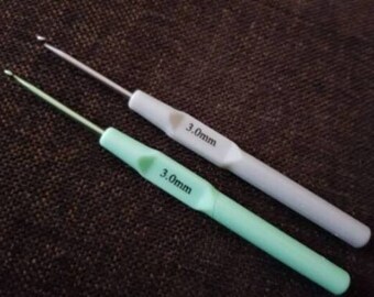 Könnte beinhalten: Zwei Häkelnadeln mit 3,0 mm, eine weiße und eine hellgrüne.