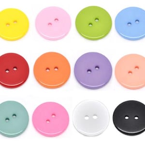 Könnte beinhalten: Zwölf runde Plastikknöpfe in verschiedenen Farben, darunter Gelb, Rosa, Grün, Blau, Rot, Orange, Lila, Pfirsich, Türkis, Pink, Weiß und Schwarz. Jeder Knopf hat zwei Löcher.