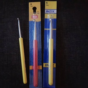 May include: Three crochet hooks packaged in plastic. The hooks are 5 mm in size and are labeled "INOX". The hooks are yellow, red, and yellow.