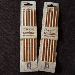 Könnte beinhalten: Eine Packung mit sechs Stricknadeln aus Holz, beschriftet mit "JMRA bamboo Stricknadeln". Die Nadeln sind 20 cm lang und in zwei Größen erhältlich: 4,5 mm und 5 mm.