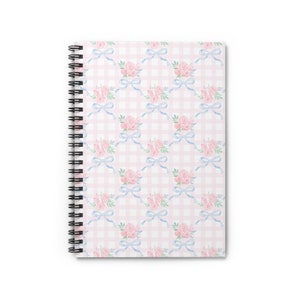 Può includere: Un quaderno a spirale con un motivo a quadri rosa e bianco, un fiocco blu e un design floreale.