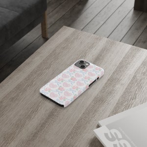 May include: A white phone case with a pink and blue watercolor pattern of hearts and bows.