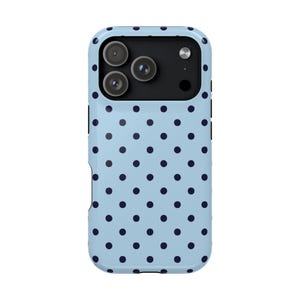 May include: A light blue phone case with a navy blue polka dot pattern. The case has a camera cutout for three lenses and a flash. The case is designed to protect the phone from damage.