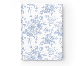 Puede incluir: Un cuaderno blanco con un patrón floral azul. El patrón presenta un diseño repetitivo de flores y hojas estilizadas.