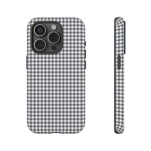 Puede incluir: Una funda de teléfono con un patrón de cuadros blanco y negro. La funda tiene un módulo de cámara negro y botones laterales negros. La funda se muestra desde el frente y el lateral.