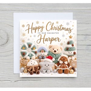 May include: A square Christmas greeting card featuring the text Happy Christmas TO OUR DAUGHTER Harper in gold script. The design includes illustrations of a crocheted wreath, a snow globe, a teddy bear, a tree, a cocoa mug, a star, and a plush toy.