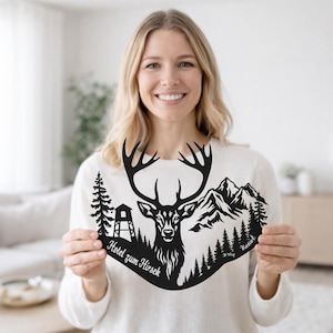 May include: Black metal wall art depicting a stag with antlers, mountains, and trees. The text "Hotel zum Hirsch" is included. The artwork is held by a person in a white sweater.