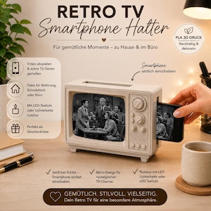 Può includere: Un supporto per smartphone rettangolare di colore beige, progettato per assomigliare a un televisore vintage. Il dispositivo presenta un'apertura frontale per lo schermo, manopole laterali e una fessura sul lato destro per inserire lo smartphone.