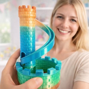 Könnte beinhalten: Ein farbenfrohes Spielzeugschloss mit einer Wendelrutsche. Das Schloss ist hauptsächlich orange, blau und grün, mit einer ziegelartigen Textur. Die Rutsche windet sich um den zentralen Turm. Das Spielzeug wird vor einer Person gehalten.
