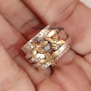 May include: A silver spinner ring with a design of bees and honeycombs. The ring is made of 925 silver and has a spinning band.