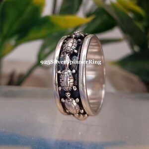 May include: A silver spinner ring with a band of turtles engraved around the circumference. The ring is 925 silver.