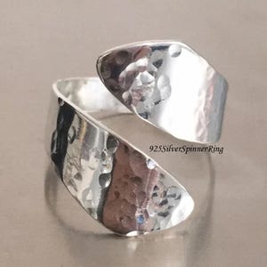 May include: A silver hammered ring with a twisted design. The ring is made of 925 sterling silver and is a spinner ring.