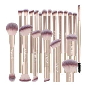 May include: A collection of makeup brushes with rose gold handles and soft, purple-tipped bristles. The brushes vary in size and shape, with the brand name "Sophia" printed on the handles. The set includes brushes for various makeup applications.