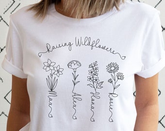 May include: White t-shirt with the text "Raising Wildflowers" and four stylised flowers with names "Max", "Allen", "Alana", and "Rosie" written underneath.