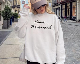 May include: A white sweatshirt with the text "Pause... Nevermind" in black script. The image also shows a tan baseball cap with the text "The Western House Casino Las Vegas, Nevada".