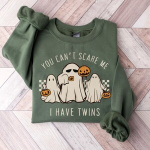 May include: Green sweatshirt with a white ghost and the text "You can't scare me I have twins" with two smaller ghosts on either side of the main ghost. Each ghost is holding a jack-o-lantern.