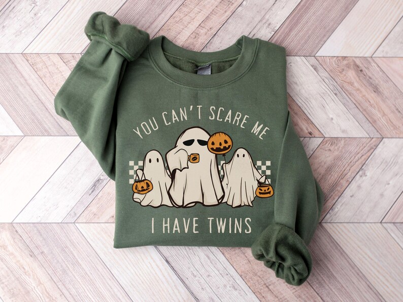May include: Green sweatshirt with a white ghost and the text "You can't scare me I have twins" with two smaller ghosts on either side of the main ghost. Each ghost is holding a jack-o-lantern.
