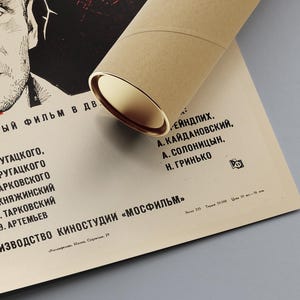May include: A black and white poster for the film "Stalker" with the names of the cast and crew listed in Russian. The poster is rolled up and tied with a brown ribbon.