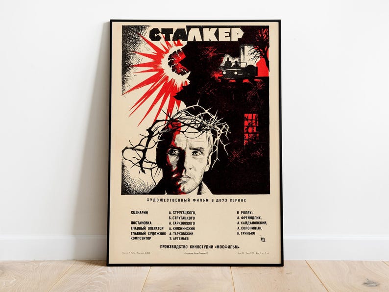 May include: A vintage movie poster for the film "Stalker" featuring a black and white image of a man with a crown of thorns on his head. The poster is in Russian and features the title "Stalker" in bold black letters. The poster also includes the film's credits, including the names of the screenwriter, director, cinematographer, and composer.