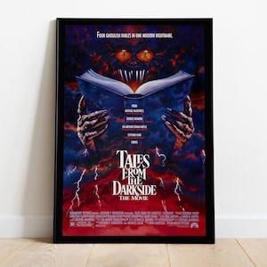 May include: A movie poster for the horror film "Tales from the Darkside: The Movie". The poster features a monstrous hand holding a book open, with a large eye peering out from the book. The poster is set against a dark, stormy sky with lightning bolts.