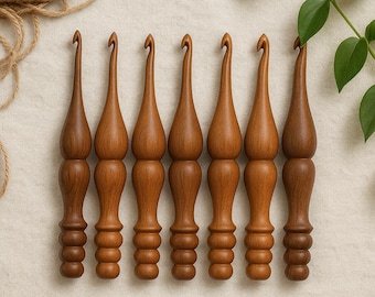 May include: A collection of seven wooden crochet hooks in varying shades of brown. The hooks have a smooth, polished finish and a distinctive ergonomic design. The handles are shaped with a series of rounded segments for a comfortable grip. The hooks are arranged on a neutral-toned fabric.
