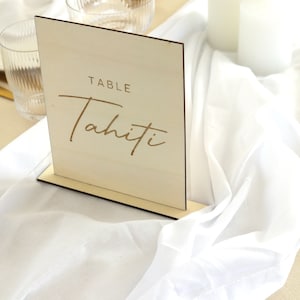May include: A wooden table number sign with the text "TABLE Tahiti" in gold lettering.
