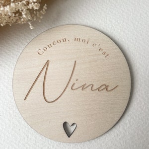 May include: A round wooden sign with the text "Coucou, moi c'est Nina" and a small heart cutout.