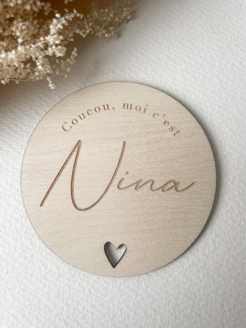 May include: A round wooden sign with the text "Coucou, moi c'est Nina" and a small heart cutout.