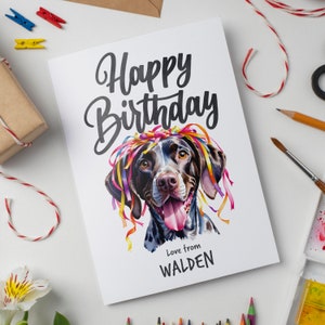 May include: A birthday card featuring a watercolour illustration of a dog wearing a colourful party hat. The card says "Happy Birthday" and "Love from WALDEN".
