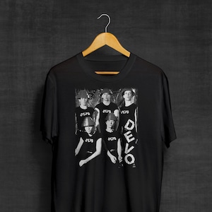 May include: Black t-shirt with a white and gray image of a band, the band members are wearing hats and the word "DEVO" is printed on the shirt.