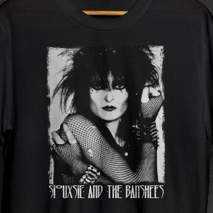 May include: Black and white graphic t-shirt featuring a photo of Siouxsie Sioux, lead singer of Siouxsie and the Banshees, with the band's name printed below the image.