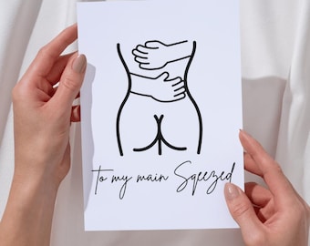 May include: A white card with a black line drawing of a torso being hugged. The text "To my main Squeezed" is written in a cursive font below the drawing. The card is held by two hands.
